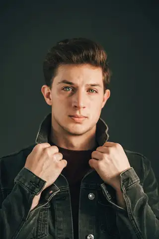 A posed studio portrait of a young man in a denim jacket, a stock photo of a stranger