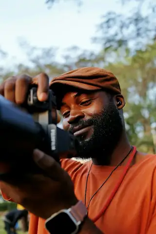 A camera operator in a cap looking through a camera viewfinder