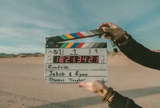Hands holding up a filled-in clapperboard against a desert sky