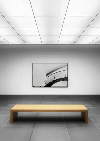 A computer-perfect white gallery with a single framed print above a wooden bench