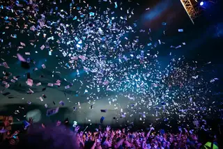 Confetti falling over a concert crowd under stage lights