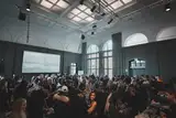 A packed hall with arched windows and a screen at the front