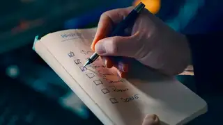 A hand ticking items off a paper checklist with a pen