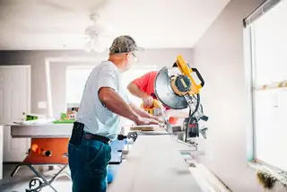 A handyman cutting trim at a miter saw