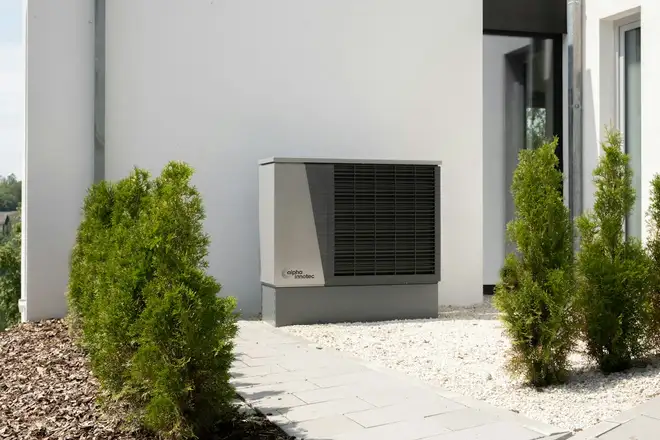 After: a new heat pump on a pad beside a white house