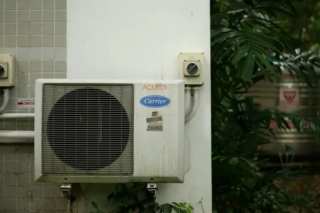 Before: an old, grimy air conditioning unit beside a house