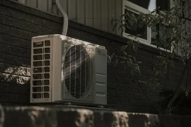 An outdoor air conditioning condenser against a dark wall