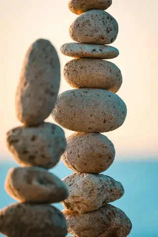 A tall stack of smooth pebbles against a blurred blue sea, the kind found on every spa flyer