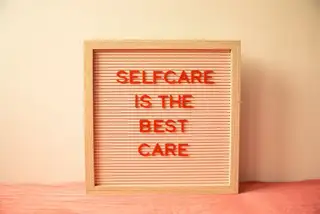 A pink letter board reading self care is the best care on a peach background